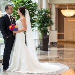 A bride and groom posing in the hallway of the Omni Park West Farmer's Branch