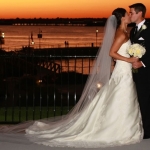 a bride and groom kissing on the patio wedding reception venue with sunset and lake in the background at the hilton rockwall dallas