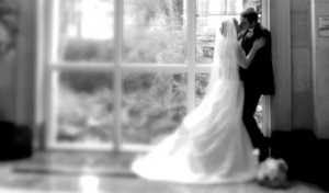 The bride and groom here are kissing in front of a window of a hallway at the Rosewood Crescent Hotel in Dallas Texas