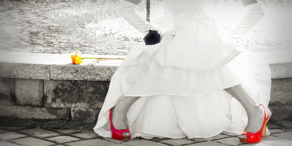 a bride in a wedding dress with red shoes sitting in front of a beautiful water fountain in Dallas Texas