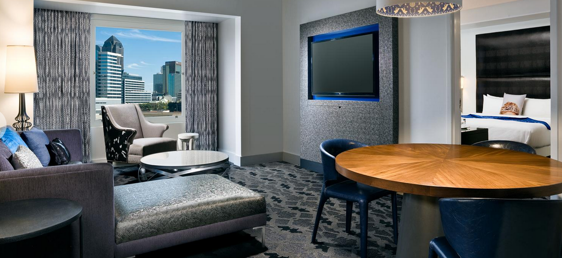 the fantastic suite at the w hotel Dallas texas has a dining table and sitting area with a flat-screen tv along with a private bedroom with a king bed