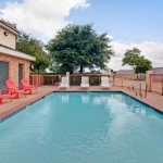 this is an outdoor pool located at the super 8 arlington tx sw with red and white lounger chairs