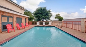 this is an outdoor pool located at the super 8 arlington tx sw with red and white lounger chairs