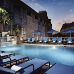 the outdoor pool at the Rosewood Crescent is luxuriously appointed with a waterfall, lounge chairs and umbrellas